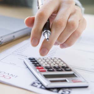 An up close image of a hand using a digital calculator